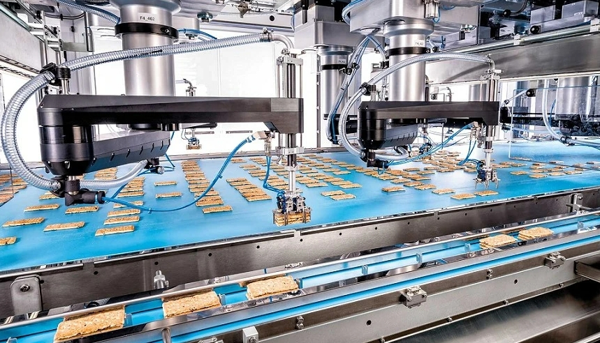 Pick and Place robots pick up baked goods and place them with millimeter precision. The image shows Pick and Place robots that group cookies into piles before later packaging.